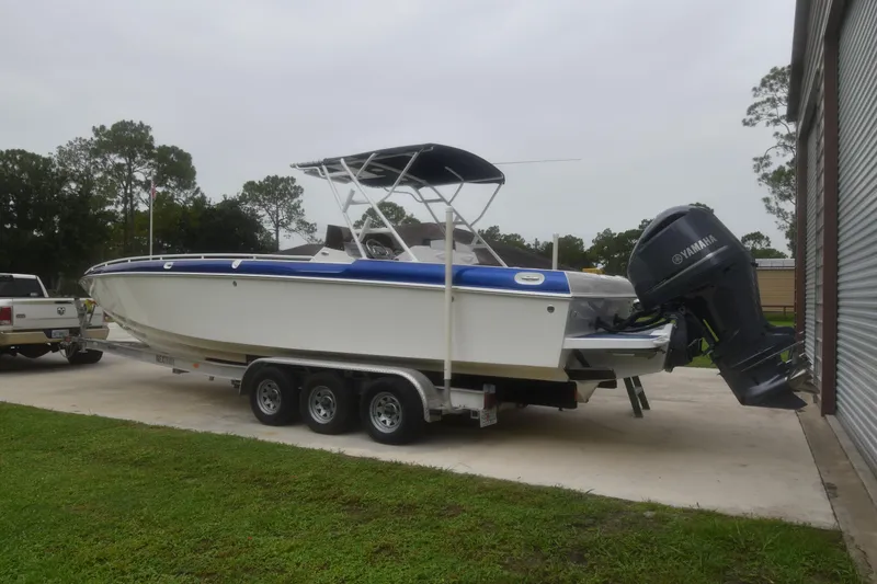 Slide: The Image of 1984 Chris-Craft Scorpion boat on trailer with outboard motor, parked outdoors. - 3