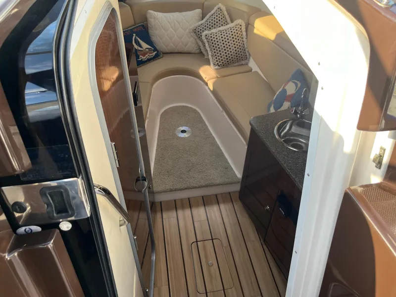 Slide: The Image of 2013 Regal 30 Express cabin interior with seating, cushions, and kitchenette. - 14