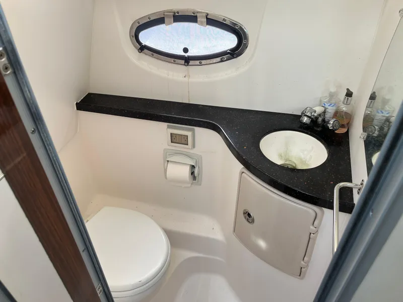 Slide: The Image of 2013 Regal 30 Express boat bathroom with sink, toilet, and porthole window. - 18