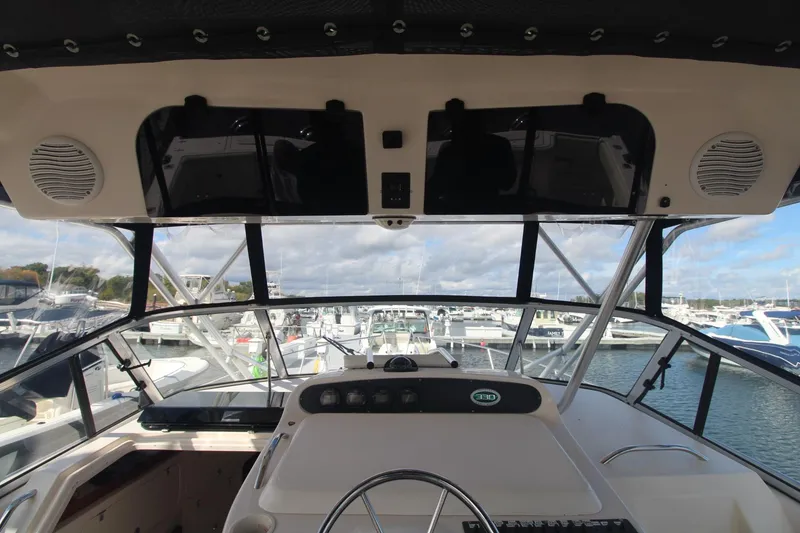 Slide: The Image of 2001 Grady-White Express 330 boat cockpit with marina view, featuring steering wheel and dashboard. - 19