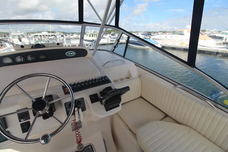 Slide: The Image of 2001 Grady-White Express 330 boat cockpit with steering wheel, control panel, and marina view. - 20
