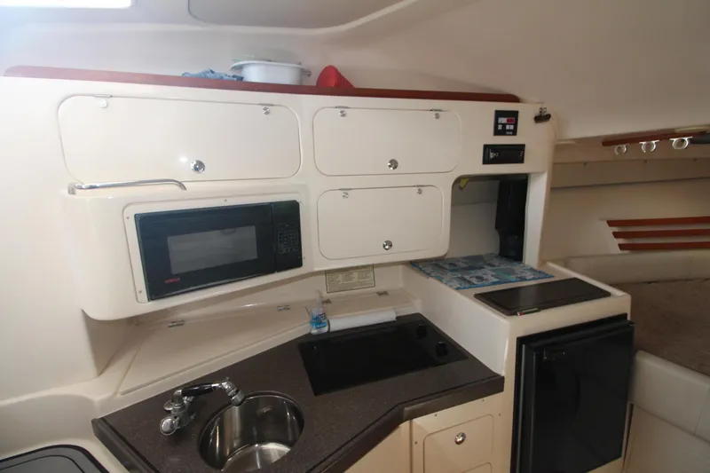 Slide: The Image of 2001 Grady-White Express 330 boat kitchen with sink, microwave, and storage cabinets. - 32