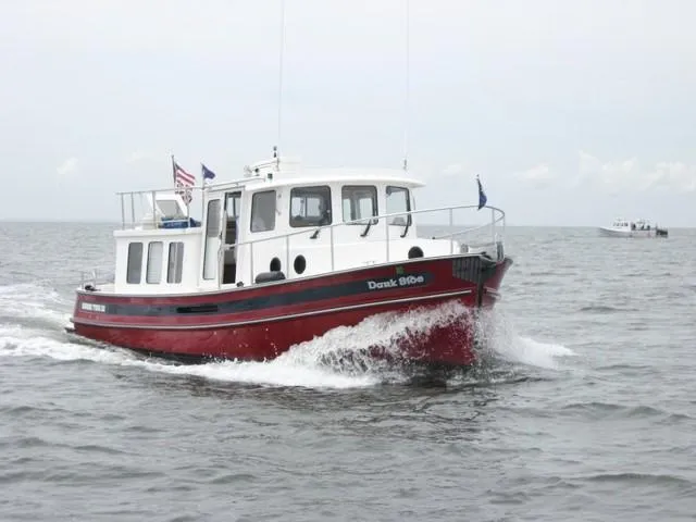 Slide: The Image of 2005 Nordic Tug 32 cruising on open water, red hull, white cabin. - 0