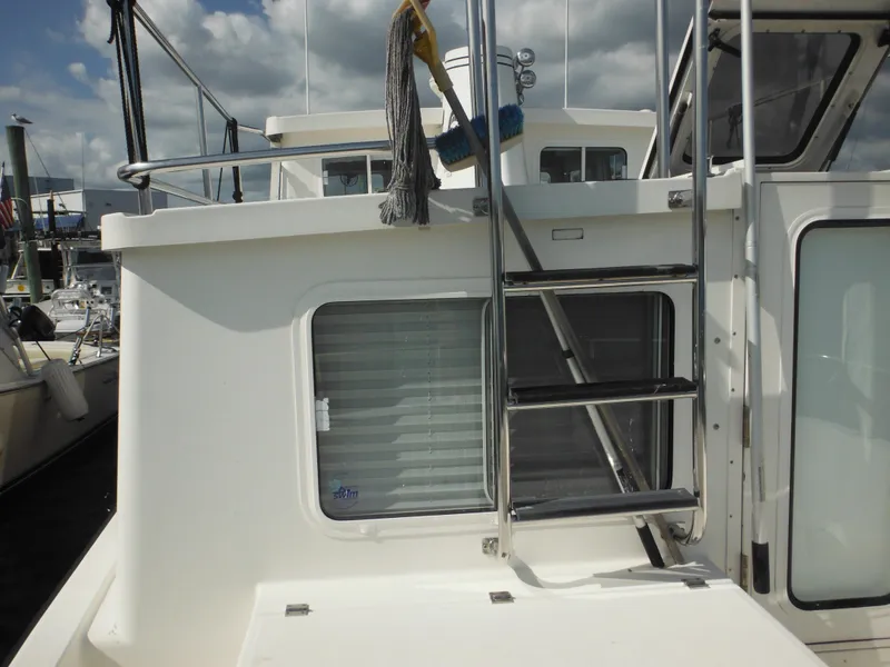 Slide: The Image of 2005 Nordic Tug 32 boat exterior with ladder and window, docked under cloudy sky. - 15