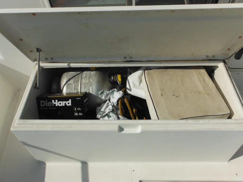 Slide: The Image of Open storage compartment on 2005 Nordic Tug 32 with DieHard battery and miscellaneous items. - 18