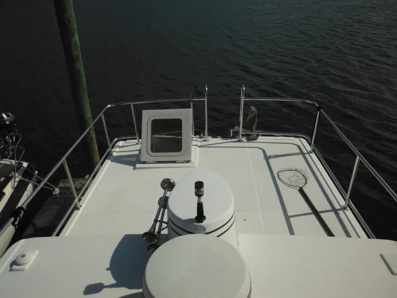 Slide: The Image of 2005 Nordic Tug 32 boat deck with railing and hatch, docked by the water. - 25