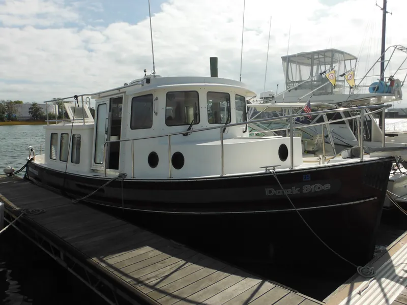 Slide: The Image of 2005 Nordic Tug 32 docked at marina under cloudy sky. - 3