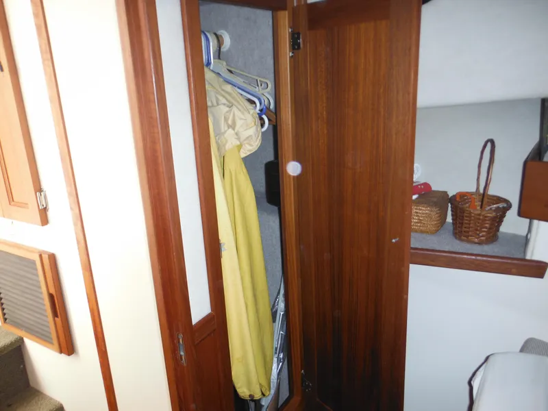 Slide: The Image of Nordic Tug 32 (2005) interior closet with wooden doors and hanging clothes. - 48
