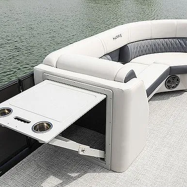 Slide: The Image of 2023 Harris 230 Sunliner boat interior with white seating and fold-out table on a lake. - 6