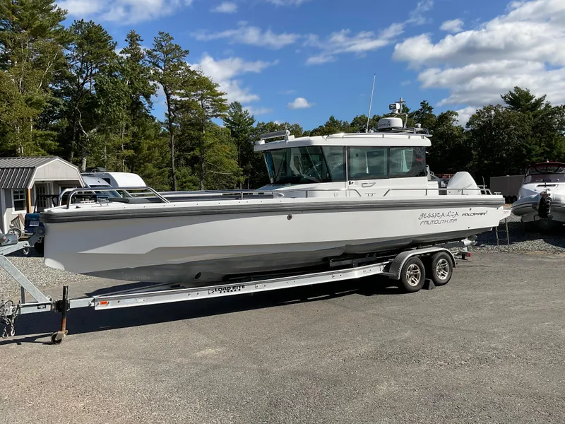 Slide: The Image of 2020 Axopar 28 boat on trailer, parked outdoors under a clear sky. - 2