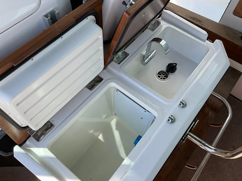 Slide: The Image of 2020 Axopar 28 boat sink and storage compartments with open lids. - 21