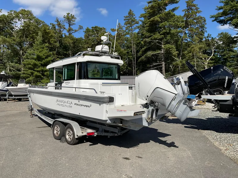 Slide: The Image of 2020 Axopar 28 boat on trailer, parked outdoors with trees in the background. - 5