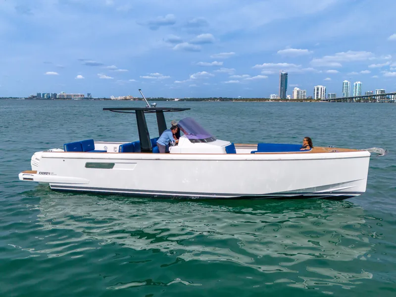 Slide: The Image of 2019 Fjord 38 Xpress boat cruising on calm waters with city skyline in background. - 15