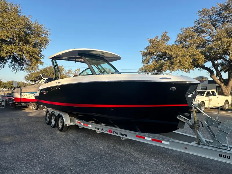 The Image of 2025 Monterey Elite 30 OB boat on trailer, parked outdoors under clear sky. - 0