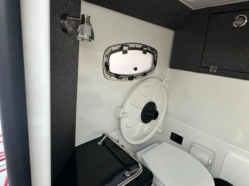 Slide: The Image of Interior of 2025 Monterey Elite 30 OB boat, featuring a compact bathroom with porthole and toilet. - 28