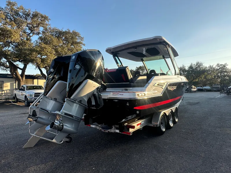 Slide: The Image of 2025 Monterey Elite 30 OB boat with dual outboard engines, parked outdoors. - 4