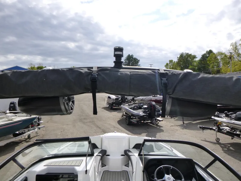 Slide: The Image of 2021 Yamaha Boats 212S with covered bimini top, parked in a lot under cloudy skies. - 12