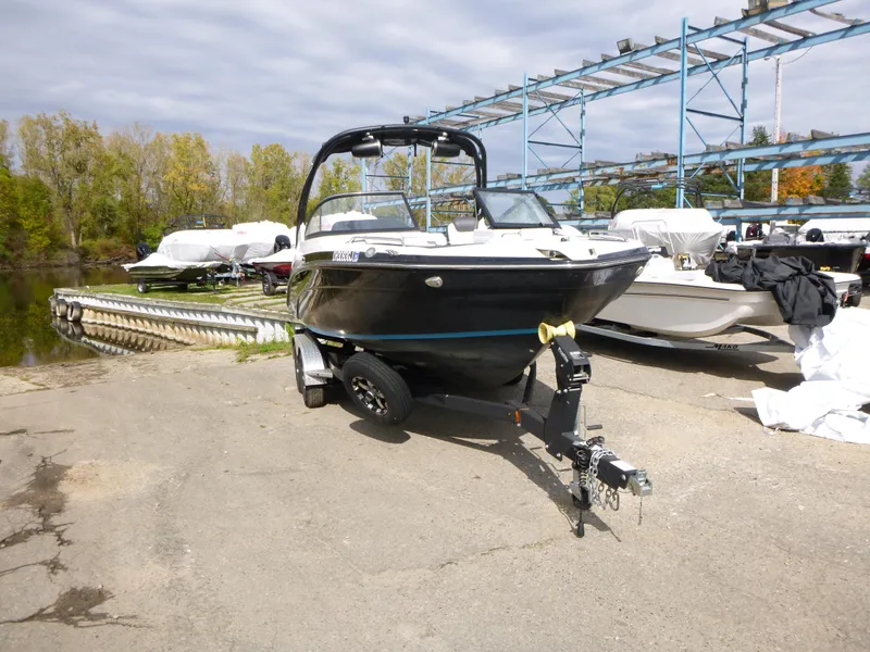 Slide: The Image of 2021 Yamaha Boats 212S on trailer in marina, surrounded by other boats. - 3