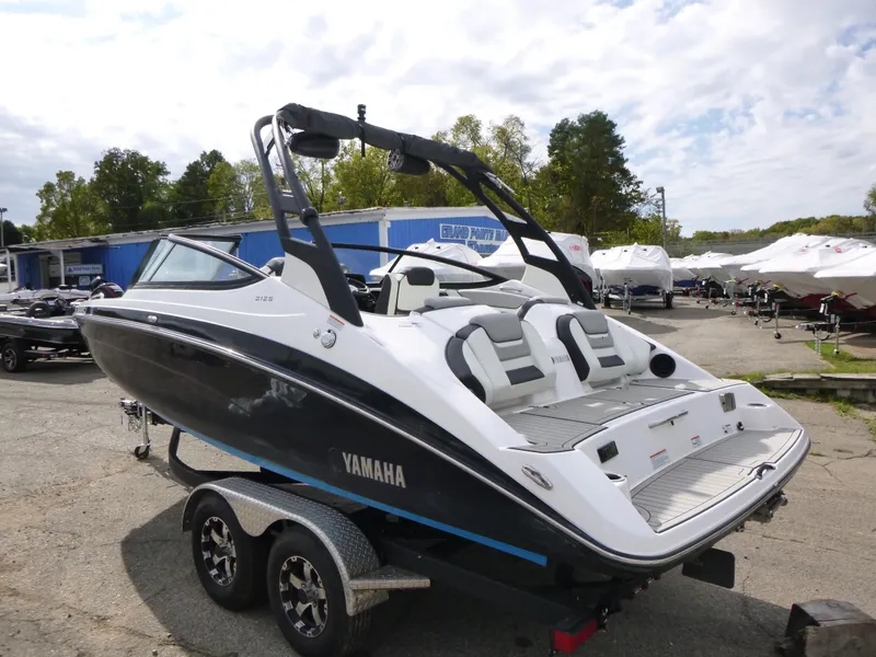 Slide: The Image of 2021 Yamaha Boats 212S on trailer, sleek design, outdoor dealership setting. - 6