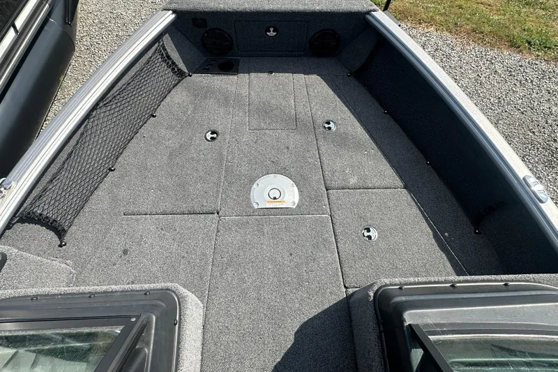 Slide: The Image of 2025 Lund 1775 Impact XS Sport boat interior with carpeted deck and storage compartments. - 16