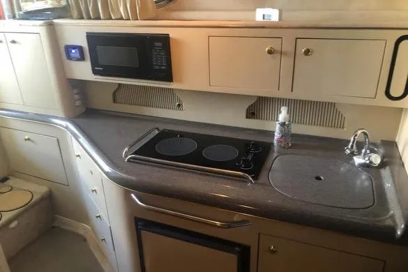 Slide: The Image of 1998 Sea Ray 310 yacht kitchen with stove, microwave, and sink. - 12