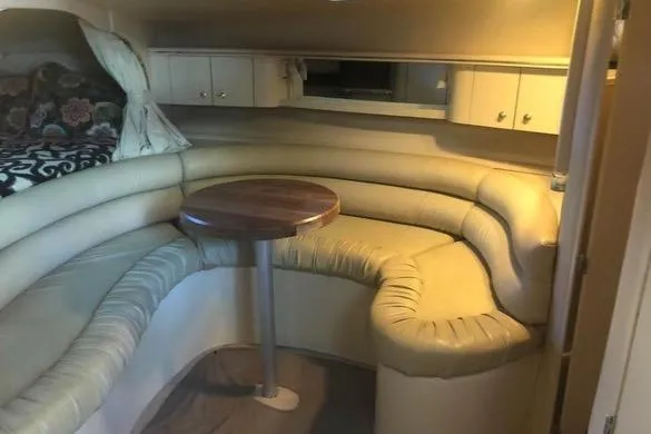 Slide: The Image of 1998 Sea Ray 310 interior with curved seating and wooden table. - 13