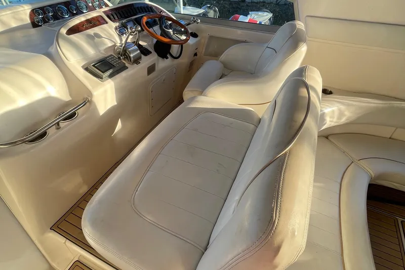 Slide: The Image of Interior of a 1998 Sea Ray 310 boat with white leather seating and wooden accents. - 5