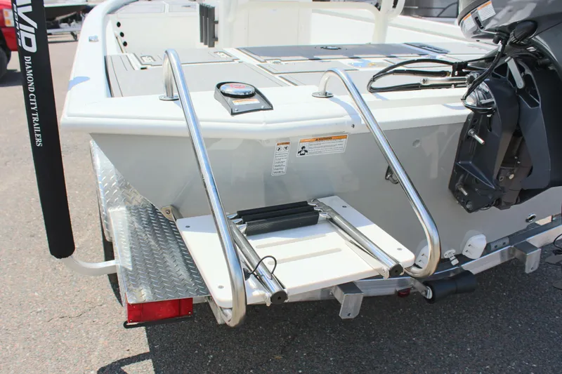 Slide: The Image of 2024 Avid 19 FSX boat with rear ladder and motor, parked on a trailer. - 9