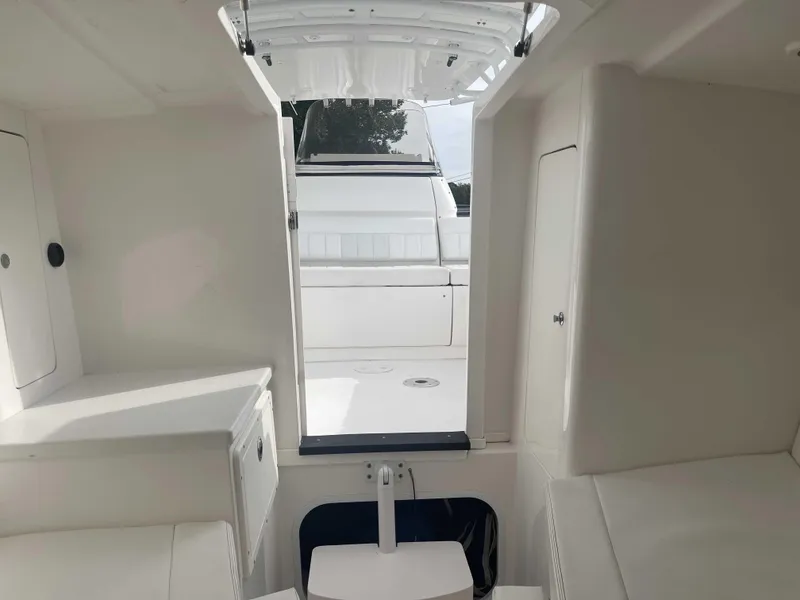 Slide: The Image of Interior view of 2013 Intrepid 327 Cuddy boat, featuring white cabin space. - 18