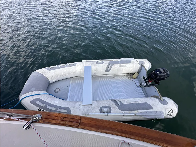 Slide: The Image of Inflatable dinghy moored beside 2001 Island Packet 320 sailboat on calm water. - 10