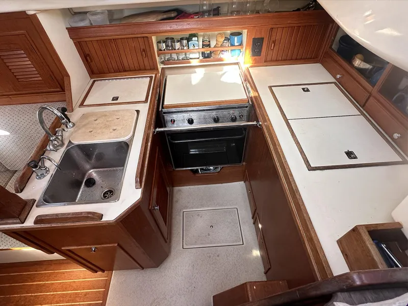 Slide: The Image of 2001 Island Packet 320 yacht kitchen with stove, sink, and wooden cabinetry. - 11