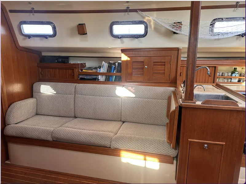 Slide: The Image of Interior of 2001 Island Packet 320 sailboat with cushioned seating and wooden cabinetry. - 13