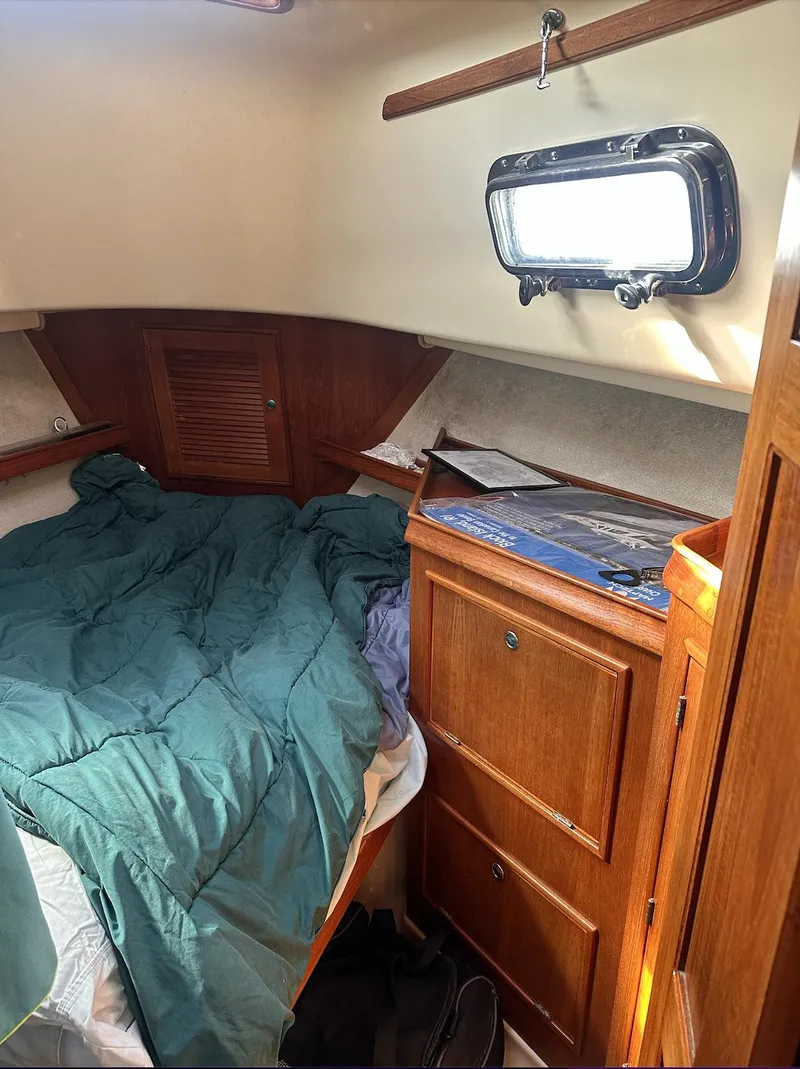 Slide: The Image of 2001 Island Packet 320 cabin interior with bed, wooden cabinetry, and porthole window. - 20