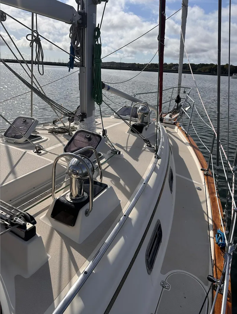 Slide: The Image of 2001 Island Packet 320 sailboat deck with rigging, on calm waters under a cloudy sky. - 3