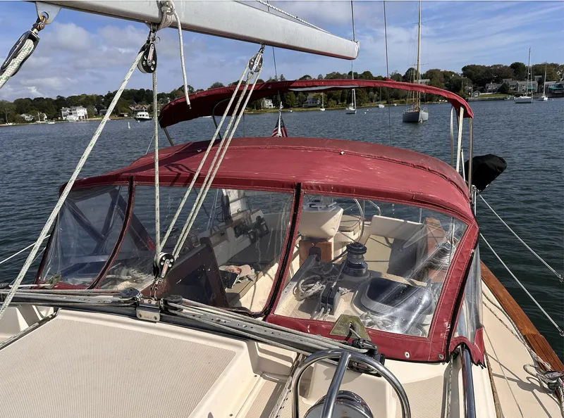 Slide: The Image of 2001 Island Packet 320 sailboat with red canopy, docked in a serene harbor. - 4