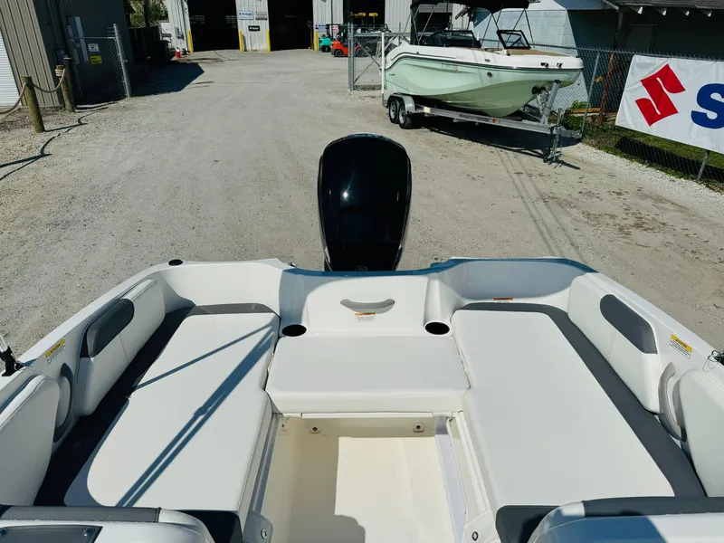 Slide: The Image of 2025 Bayliner Element E18 boat interior with seating and motor, parked outdoors. - 10