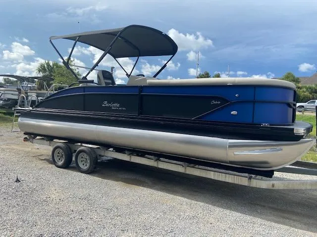 Slide: The Image of 2023 Barletta Cabrio 24 UC pontoon boat on trailer, featuring sleek design and canopy. - 2
