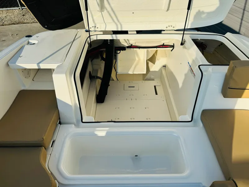 Slide: The Image of 2025 Bayliner VR6 Bowrider OB interior storage compartment with open hatch and seating area. - 14