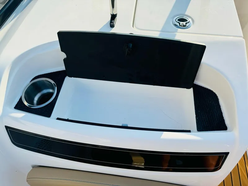 Slide: The Image of 2025 Bayliner VR6 Bowrider OB boat interior with open storage compartment and cup holder. - 19
