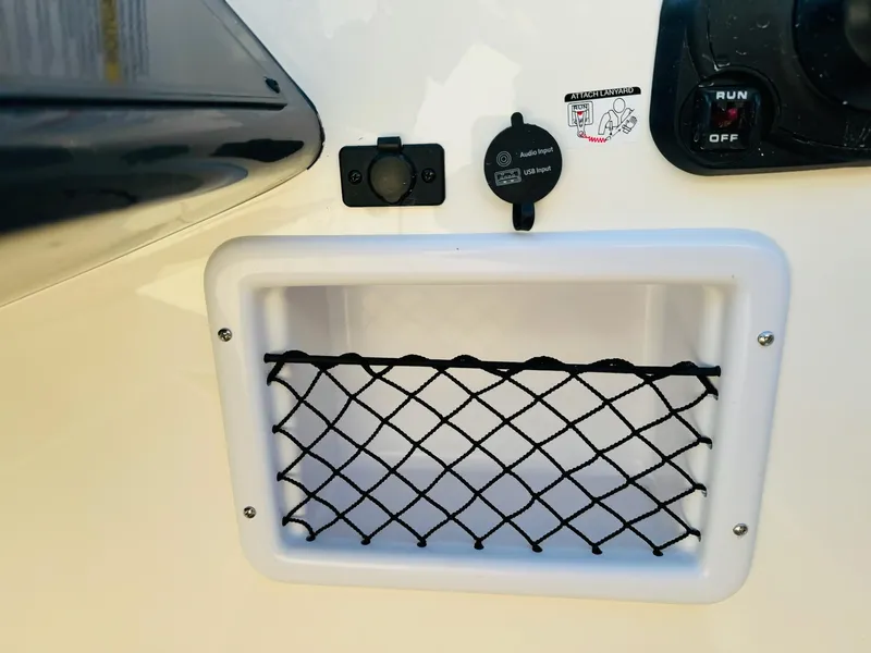 Slide: The Image of 2025 Bayliner VR6 Bowrider OB storage compartment with netting and control panel. - 24