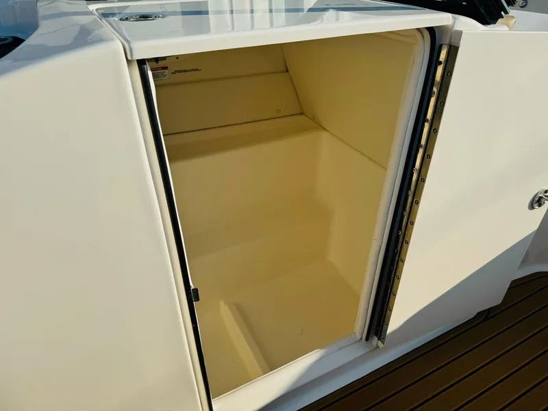 Slide: The Image of 2025 Bayliner VR6 Bowrider OB storage compartment, open and empty, with white interior. - 25