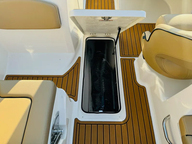 Slide: The Image of 2025 Bayliner VR6 Bowrider OB interior with open storage compartment and tan seating. - 36