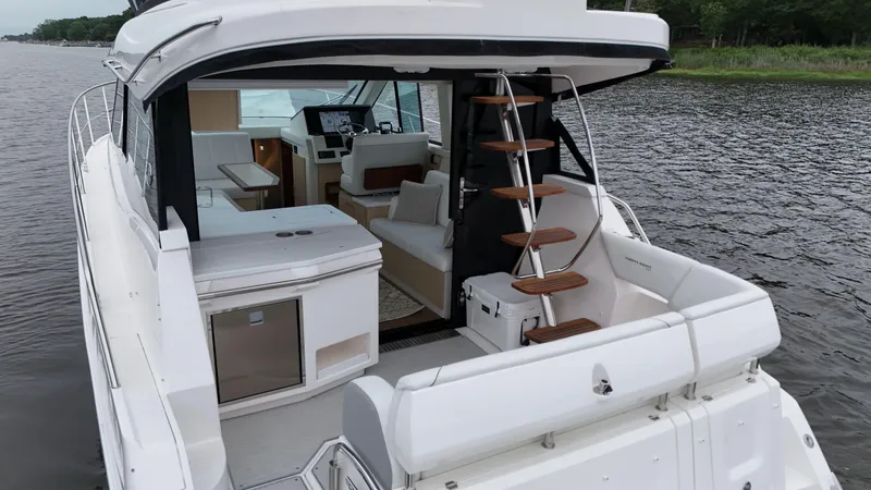 Slide: The Image of 2025 Regal 38 FXO yacht interior with modern design and spiral staircase on a calm waterway. - 11