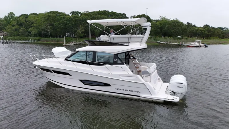 Slide: The Image of 2025 Regal 38 FXO yacht on calm water, featuring sleek design and Yamaha outboard engines. - 5