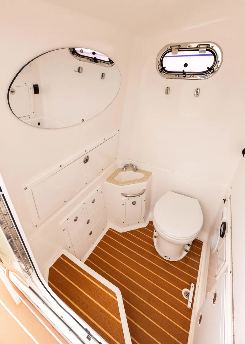 Slide: The Image of 2017 Edgewater Center Console boat bathroom with wood flooring and oval mirror. - 13