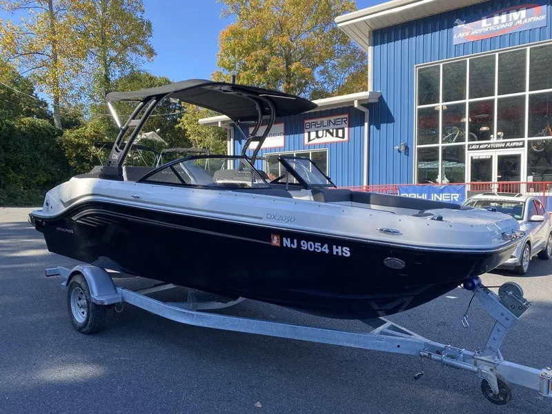 The Image of 2023 Bayliner DX2050 boat on trailer outside dealership. - 1