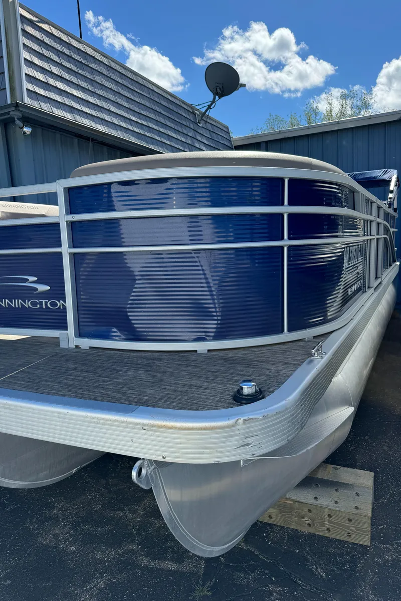 Slide: The Image of 2022 Bennington Cruiser 230 pontoon boat with blue exterior, docked under a clear sky. - 3