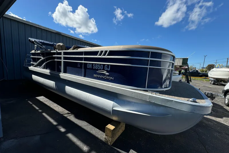 Slide: The Image of 2022 Bennington Cruiser 230 pontoon boat parked outdoors under blue sky. - 4
