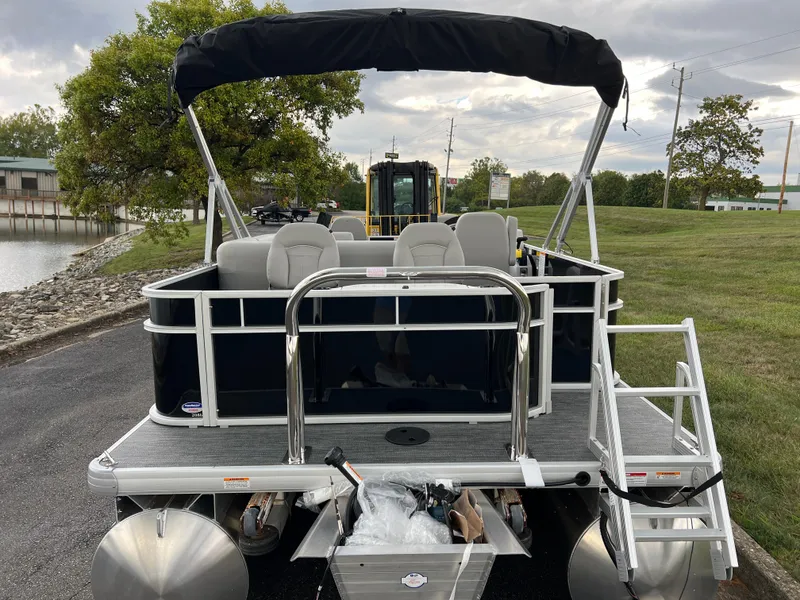 Slide: The Image of 2025 Godfrey Xperience 2086 FX pontoon boat with canopy, docked near a grassy shoreline. - 6