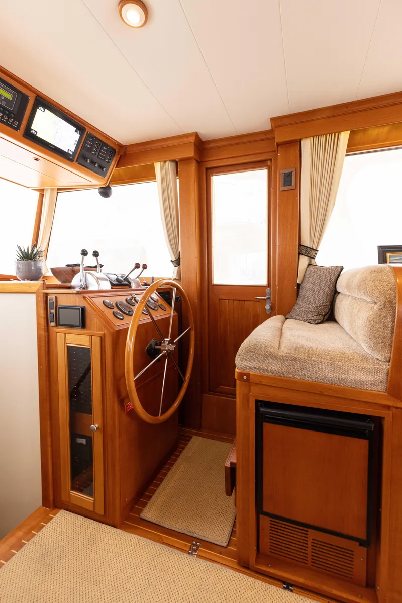 Slide: The Image of 2005 Grand Banks Europa yacht interior with wooden helm and plush seating. - 14